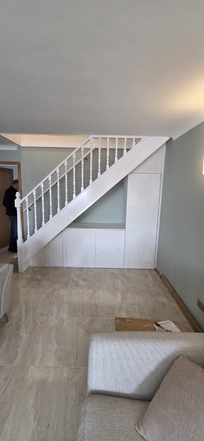 White under-stairs cupboards with a tall coat cupboard and open triangular section